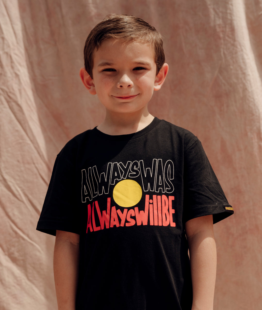 Clothing The Gaps. Black kids short sleeve T-shirt with Black, yellow and red 'always was always will be' text screen printed in centre.