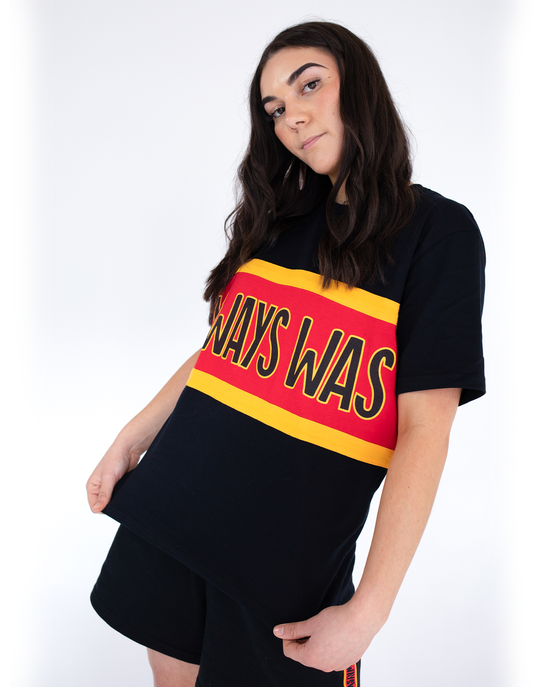 Clothing The Gaps. Power Rugby Tee. Red, black and yellow colorway. Black base tee with thick yellow top and bottom lines and red fill in mid section of jumper with big bold black text with a yellow outline in red section. Reading 'Always was' on front and on back in same text 'Always will be.' 