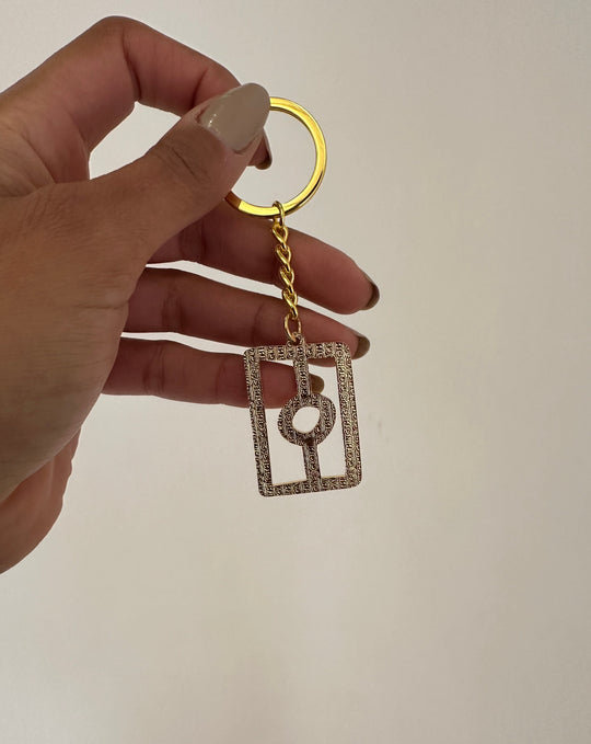 Clothing The Gaps. Flag Keyring. All gold coloured metal keyring with gold chain and loop attached to gold thick outline of Aboriginal flag. 