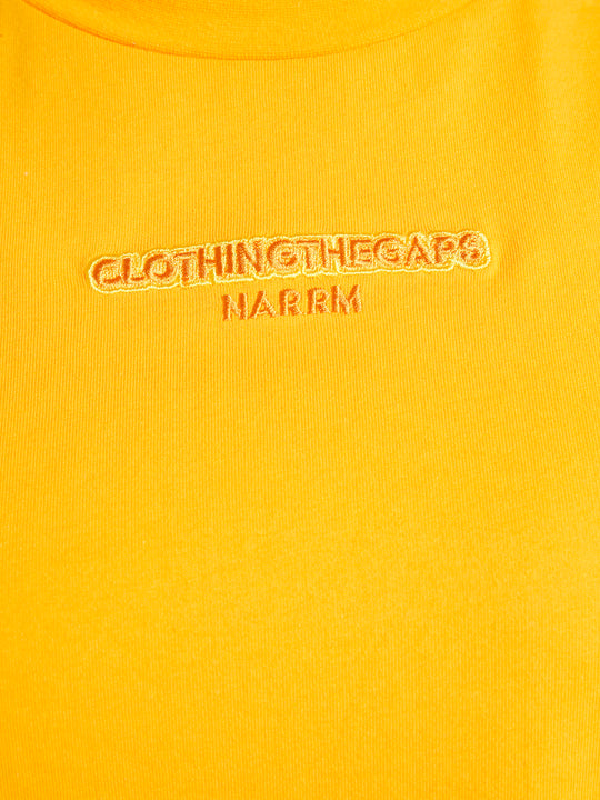 Clothing The Gaps. Sun Tee. Yellow T-shirt. With embroidered 'Clothing The Gaps' on front chest with minimalist font in a contrasting light yellow colour and 'Narrm' in a darker yellow embroidered underneath, acknowledging the land on which Clothing The Gaps operates it's social enterprise.