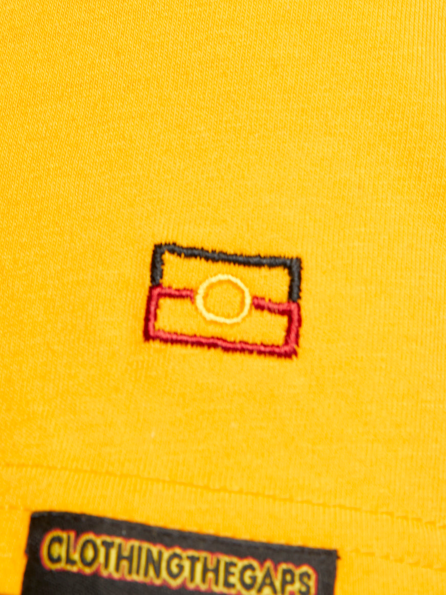 Clothing The Gaps. Sun Tee. Yellow T-shirt. With embroidered 'Clothing The Gaps' on front chest with minimalist font in a contrasting light yellow colour and 'Narrm' in a darker yellow embroidered underneath, acknowledging the land on which Clothing The Gaps operates it's social enterprise.