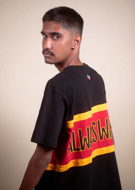 Clothing The Gaps. Power Rugby Tee. Red, black and yellow colorway. Black base tee with thick yellow top and bottom lines and red fill in mid section of jumper with big bold black text with a yellow outline in red section. Reading 'Always was' on front and on back in same text 'Always will be.' 