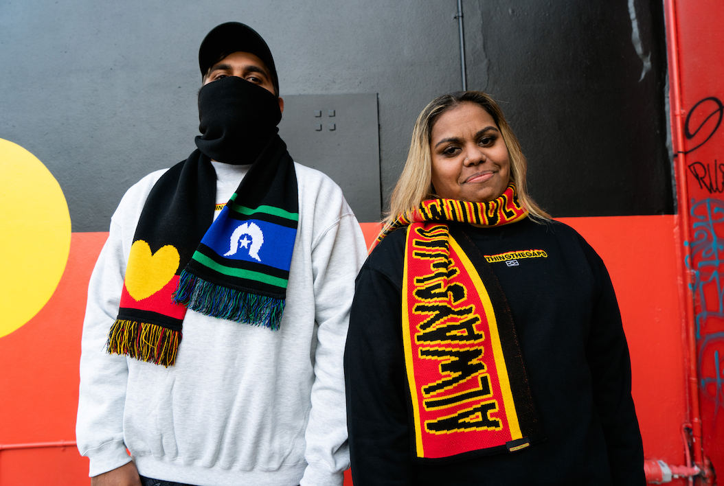 Clothing The Gaps. Power Scarf. High quality thick scarf with black bold text with a yellow outline reading 'always was always will be.' Text is on a red background with a yellow thin line then thick black trim. 