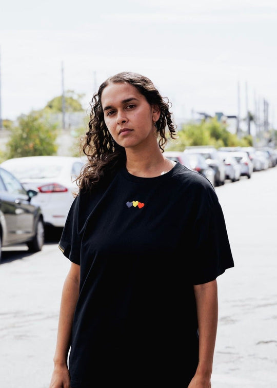 Clothing The Gaps. Blak Luv Tee. All black tee with  Red, black and yellow hearts embroiled on front the colours of the aboriginal flag.